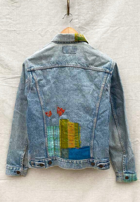 Back of blue denim jacket with fabric flowers and patches